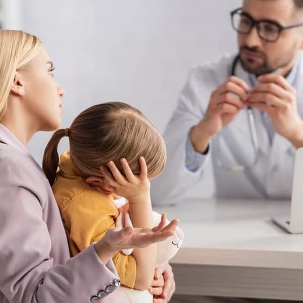 Child holding their head in pain from a migraine